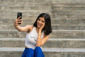 a woman sitting on steps taking a picture with her cell phone