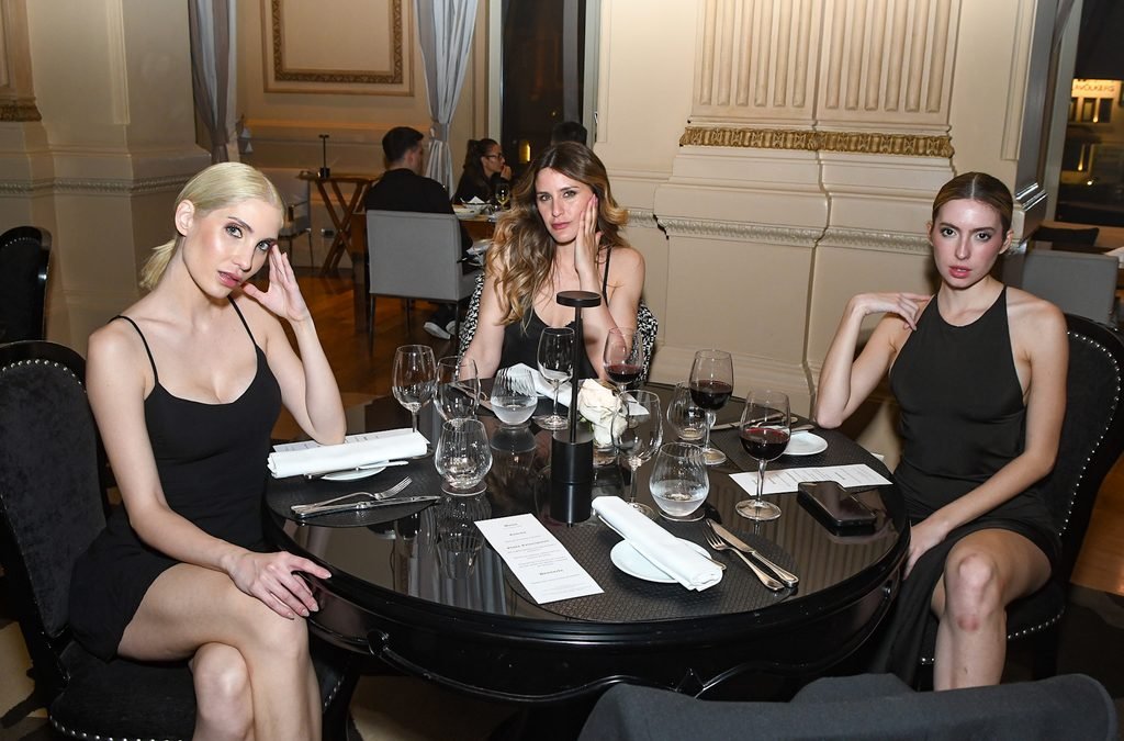 Tres invitadas con vestidos negros sentadas a la mesa durante la cena en el Renato Papiccio Runway, Sofitel Montevideo