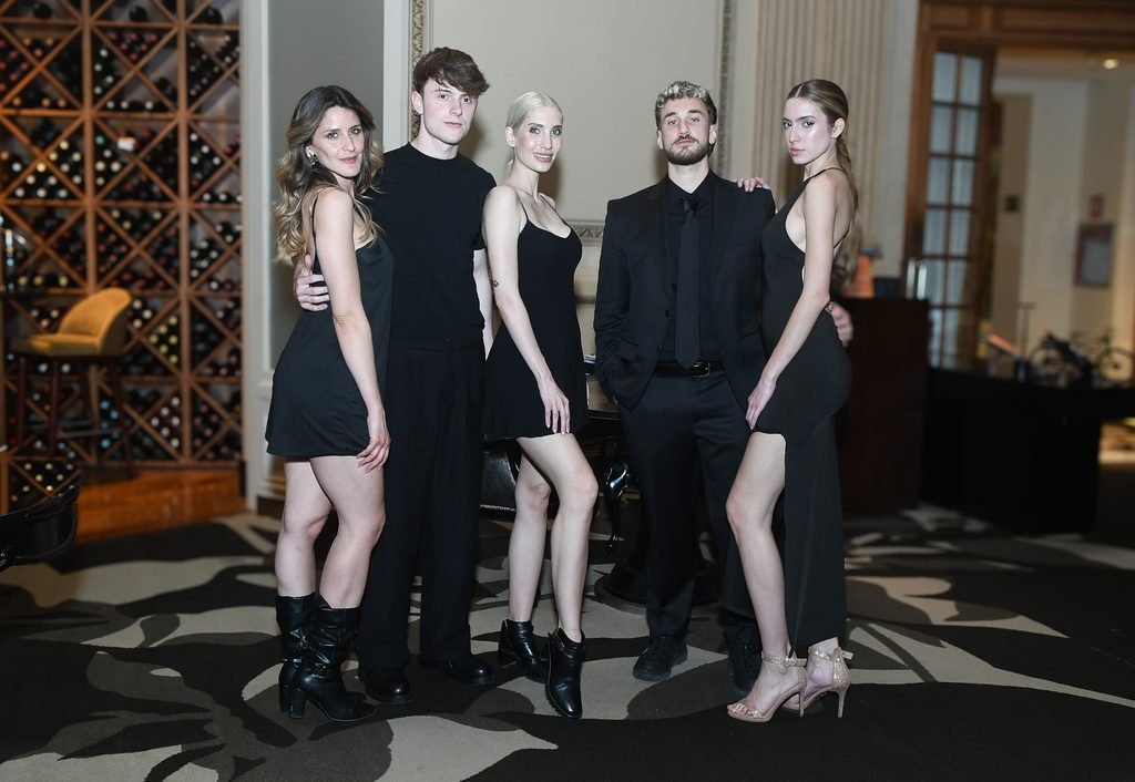 Grupo de jóvenes invitados vestidos de negro posa junto a una cava de vinos en el Sofitel Montevideo
