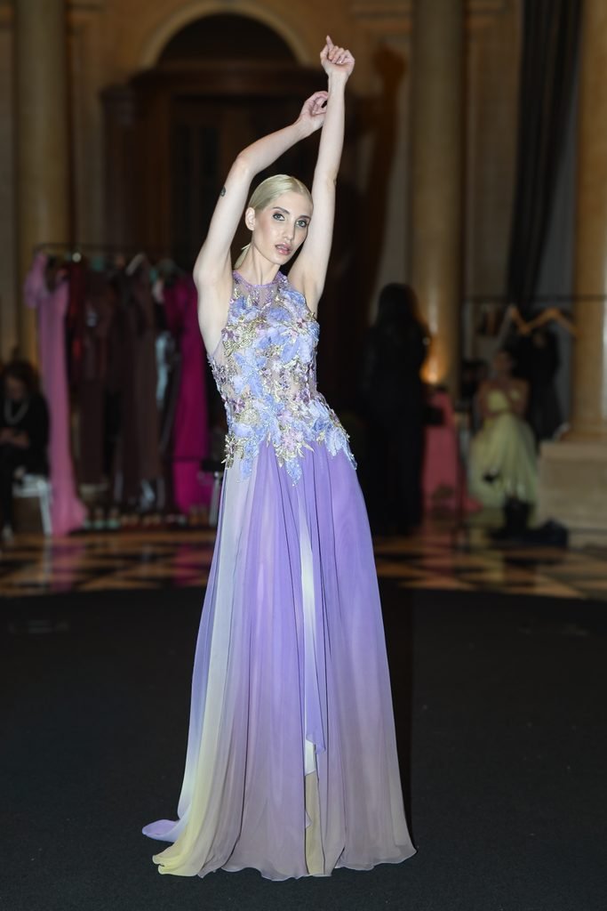 Modelo con vestido largo lavanda bordado y abertura alza los brazos en la pasarela en el Renato Papiccio Runway, Sofitel Montevideo