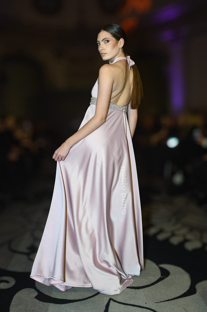 Modelo de espaldas con vestido largo de satén rosa pálido con espalda descubierta en el Renato Papiccio Runway, Sofitel Montevideo