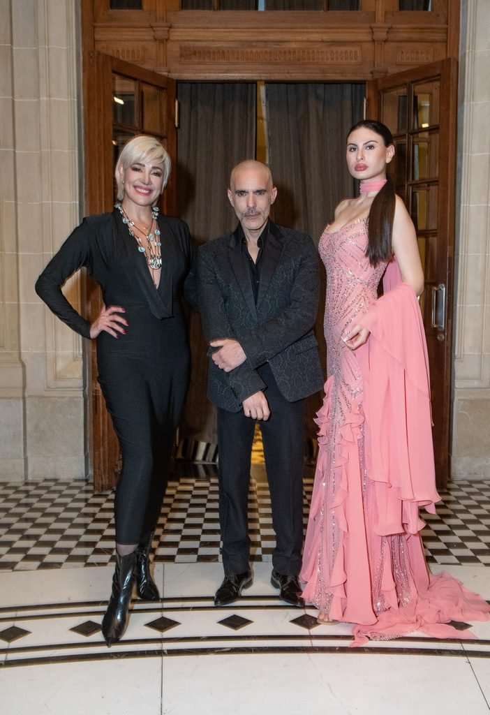 Mujer de negro, hombre de traje y modelo con vestido rosa de volados posan en el Sofitel Montevideo