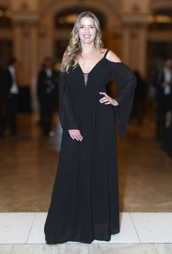 Invitada rubia con vestido largo negro de hombros descubiertos posa en el Renato Papiccio Runway, Sofitel Montevideo